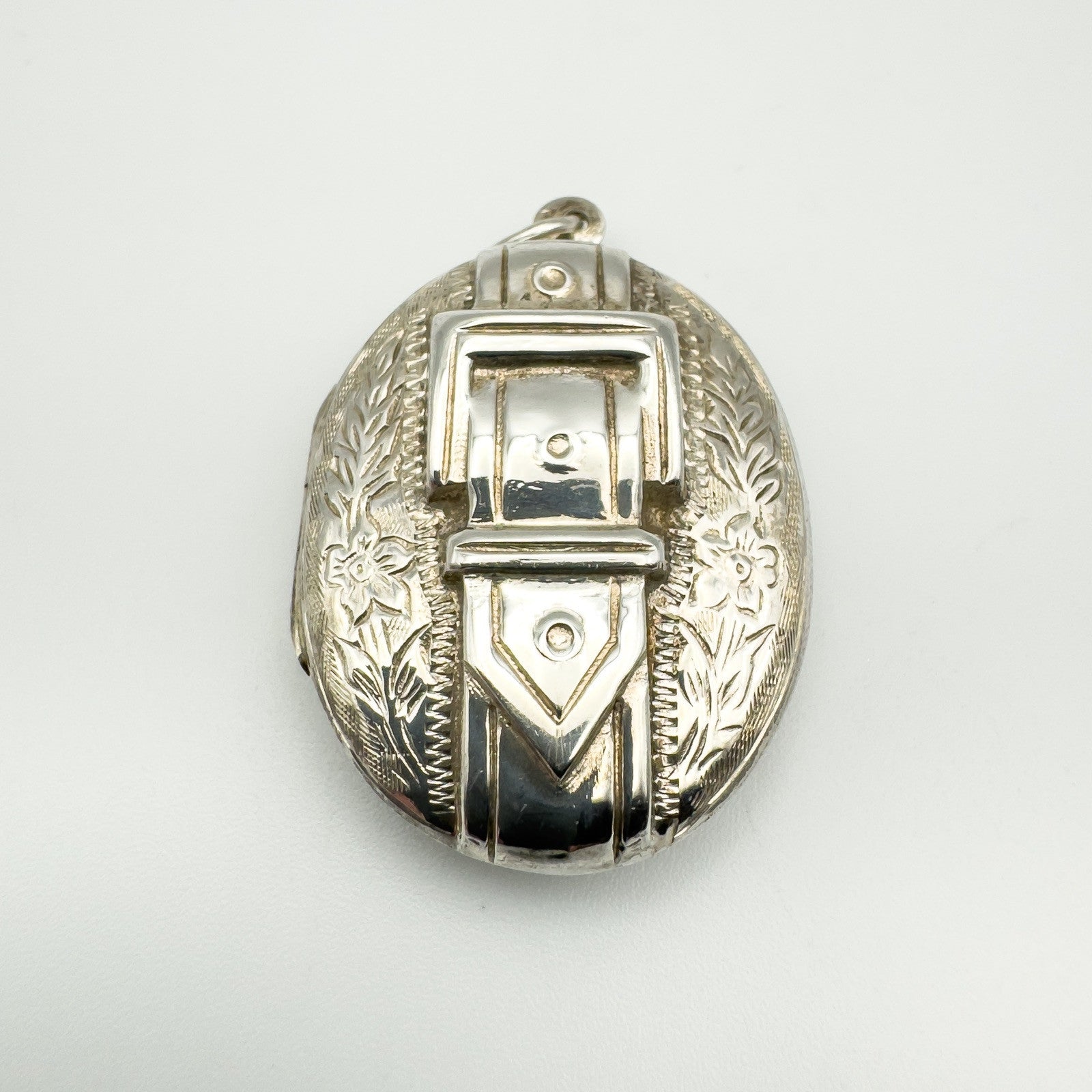 Vintage sterling silver locket with raised buckle and foliate engraving