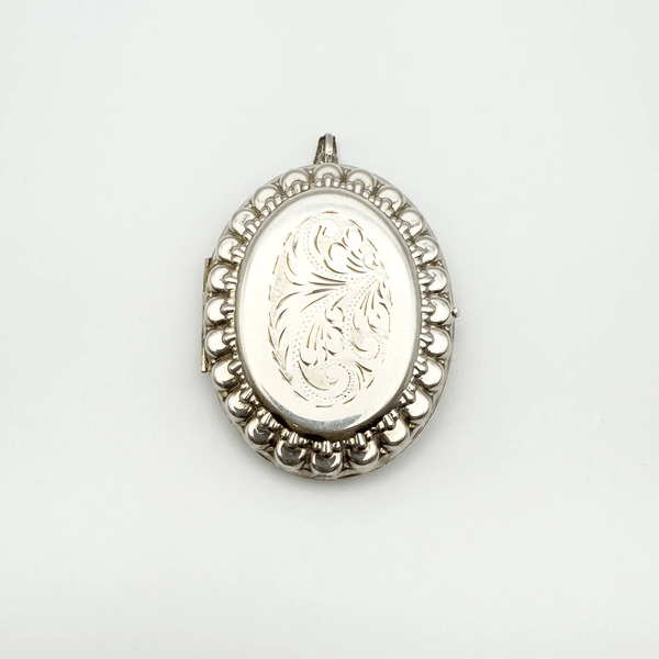 Large sterling silver locket with ornate foliate engraving on the front