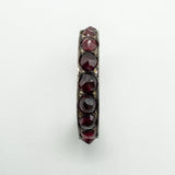 Top-down view highlighting the full row of round red garnets across the band