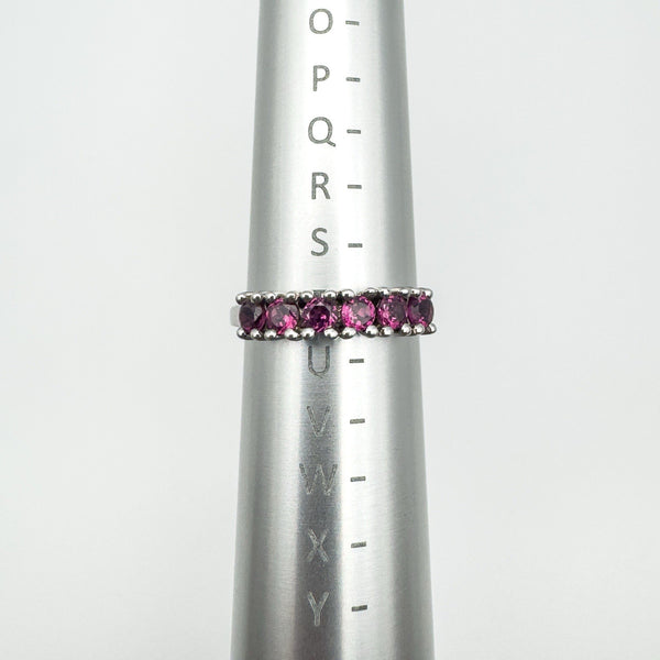 Sterling silver ring with pink rhodolite garnets shown on a metal ring sizer measuring UK size S–T