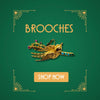 Gold bird brooch with colourful gemstones on green background