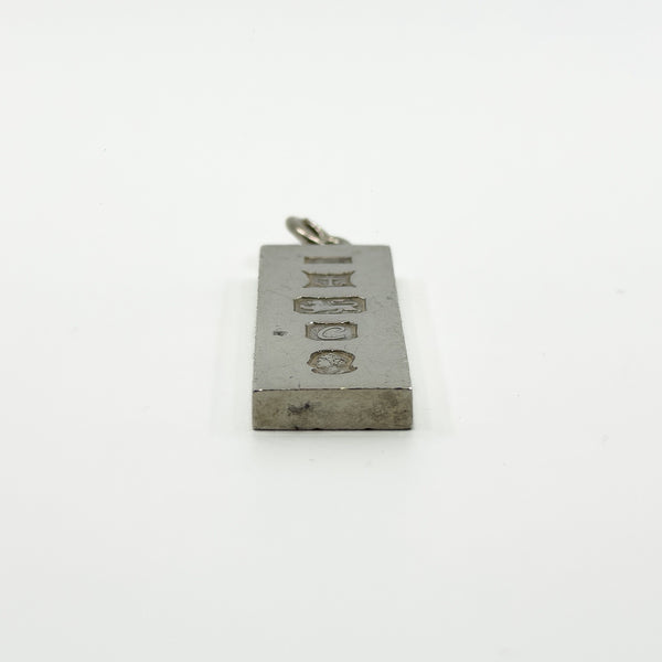 Close side view of vintage sterling silver ingot pendant with visible hallmarks and bail
