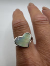 White mother of pearl heart ring shown worn on finger, natural light angle