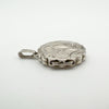 Angled side view of closed vintage silver locket showing scalloped border and hinge