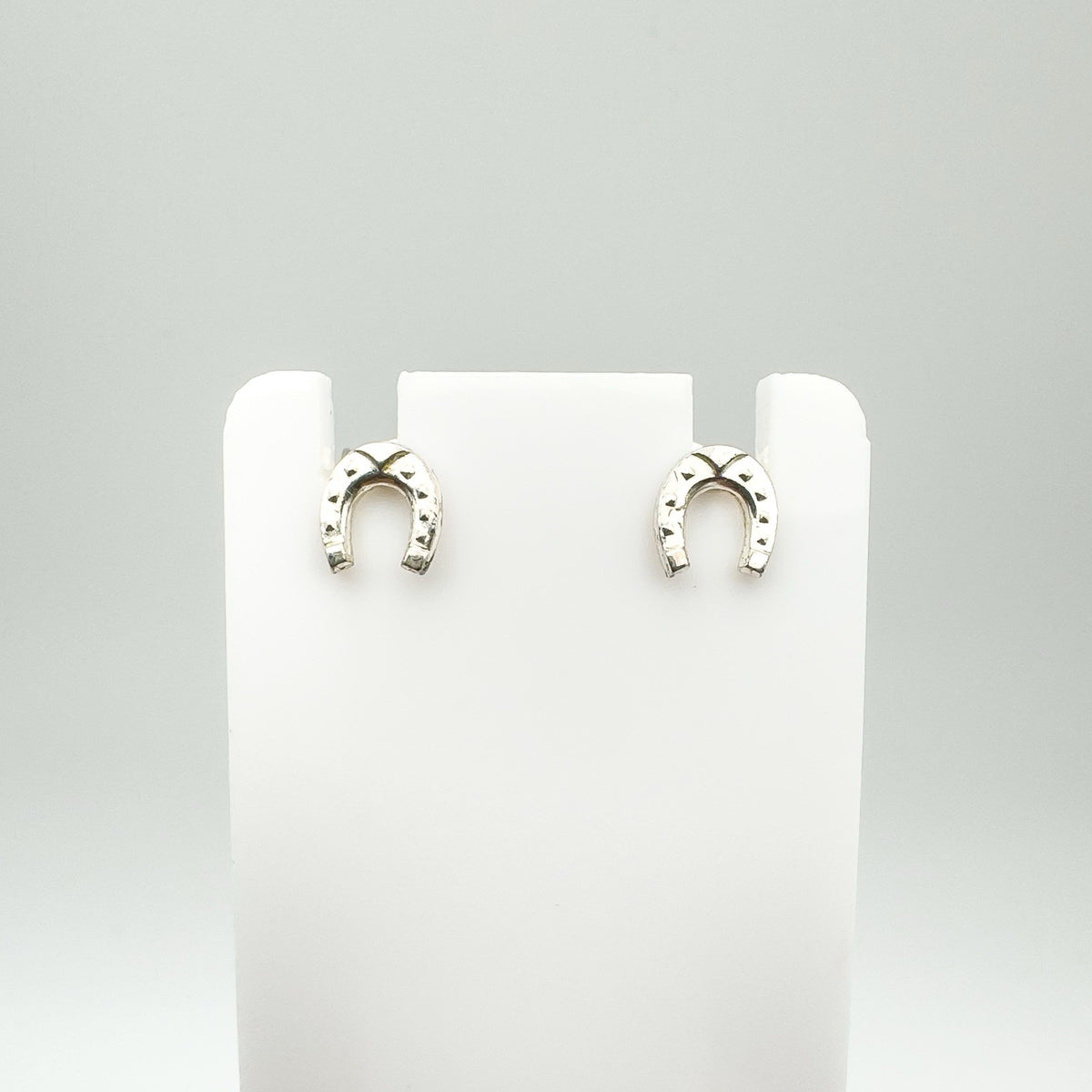 Mini sterling silver horseshoe earrings shown on white display