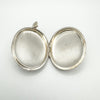 Open vintage silver locket showing inner compartments without liners