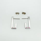 Flat lay of sterling silver J half hoop earrings showing butterfly backs and gemstone settings