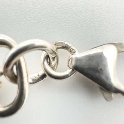Close-up of hallmark on jump ring near clasp of silver bracelet