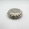 Close side angle showing foliate engraving and thick edge of silver locket