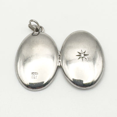 Sterling silver locket open with visible diamond and stamp