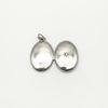 Both sides of oval silver locket open with hallmark and star detail