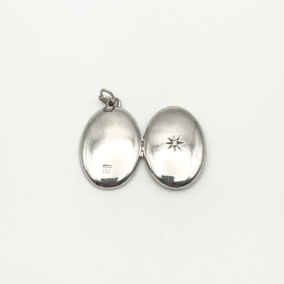 Both sides of oval silver locket open with hallmark and star detail