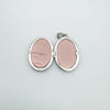 Inside of oval silver locket showing pink photo inserts