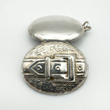Vintage silver buckle locket open to show inner hinge and foliate design