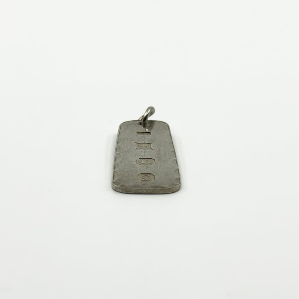 Low side view of sterling silver ingot pendant with Birmingham hallmarks and attached jump ring.