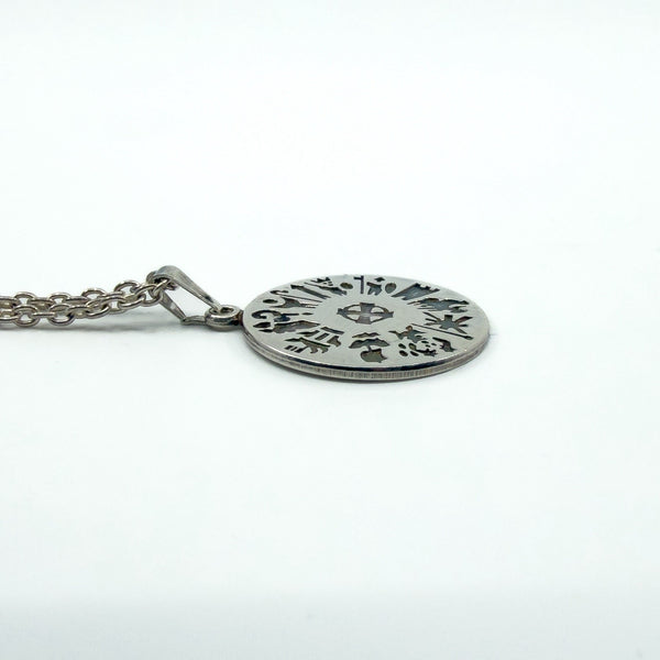 Low side profile of the sterling silver pendant disc, showing the cut-out symbols and edge detail.