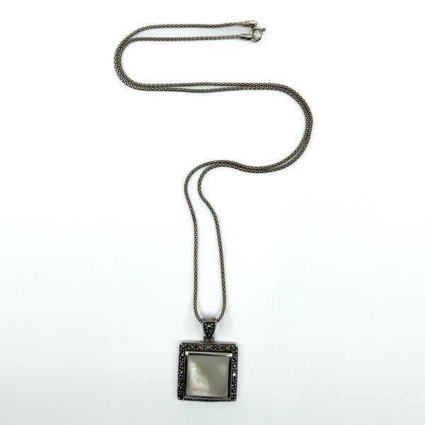Sterling silver mother of pearl and marcasite pendant shown on chain, square drop design with marcasite halo.