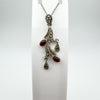 Carnelian and marcasite floral pendant displayed on white stand
