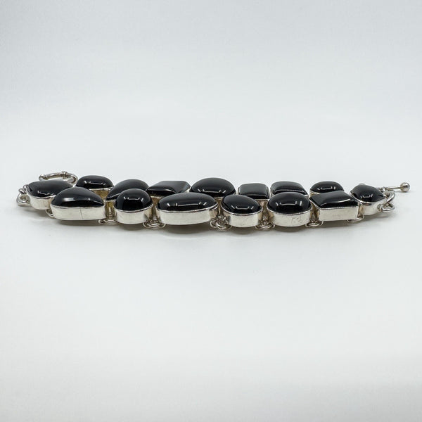 Side profile of chunky sterling silver black onyx bracelet showing raised cabochon bezel settings