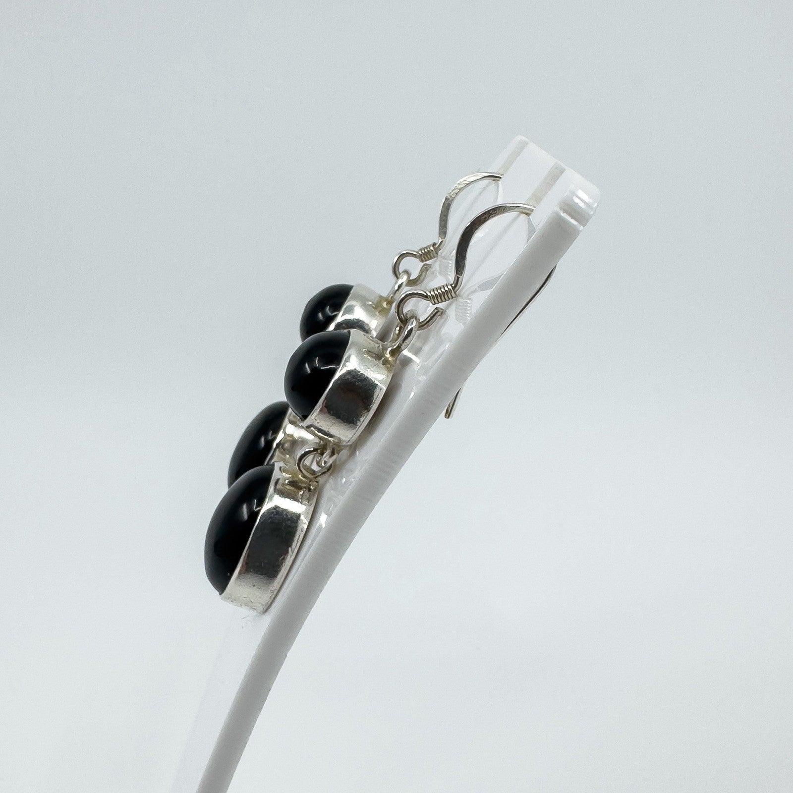 Side view of sterling silver black onyx drop earrings showing shepherd hooks and raised bezel settings