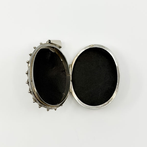 Open vintage sterling silver oval locket showing space inside for two photos or keepsakes