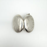Chunky sterling silver locket opened to show front engraving and plain back