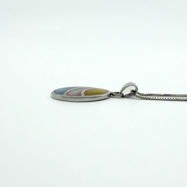 Sterling silver oval inlay pendant shown side-on while on chain, highlighting the smooth polished edge.