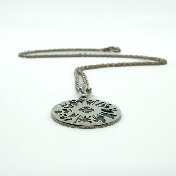 History of Ireland sterling silver pendant lying flat, front symbols visible with chain in the background.