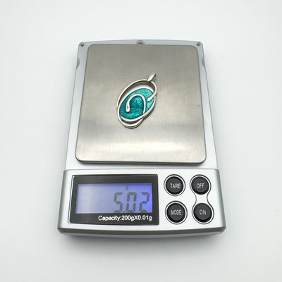 Swirly green enamel pendant on digital scales weighing 5.02 grams