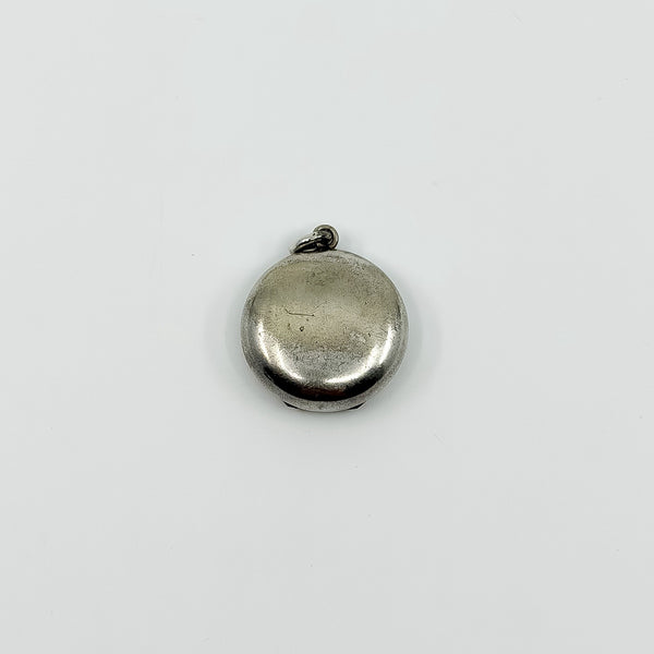 Plain back of vintage sterling silver Virgin Mary photo locket pendant showing surface wear.