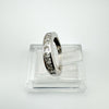 Side-angle view of a sterling silver ring with princess-cut Moissanites in a channel setting, placed on a clear stand.