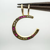 Underside of ruby and diamond horseshoe pendant shown with tweezers