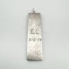 Back of sterling silver bar pendant engraved with “E•L 31.5.78” and bark-effect surface pattern