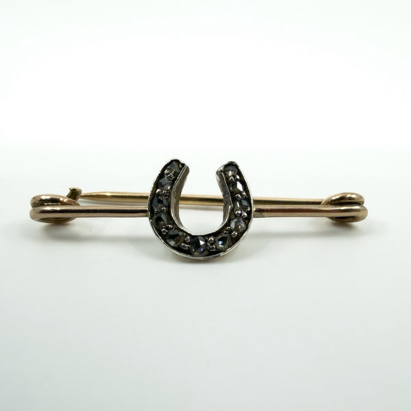 Close-up of antique 9ct gold horseshoe bar brooch with rose cut diamonds set in silver