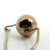 Close-up of rose gold ball drop earring showing 375 stamp and hook wire fitting
