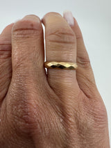 Close up of vintage 18ct rose gold faceted band ring worn on the finger showing polished detail.