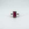 Front view of sterling silver ring with emerald cut ruby and diamond halo