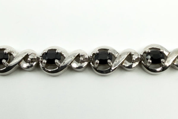 Close up of oval blue sapphires and small diamond accents in sterling silver tennis links