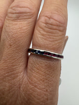 Channel set sapphire and ruby eternity ring worn on finger side profile