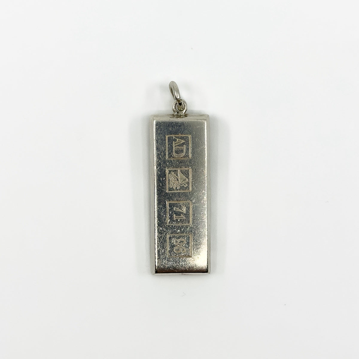 Close up of the front of a chunky sterling silver ingot pendant with Sheffield style hallmark blocks.