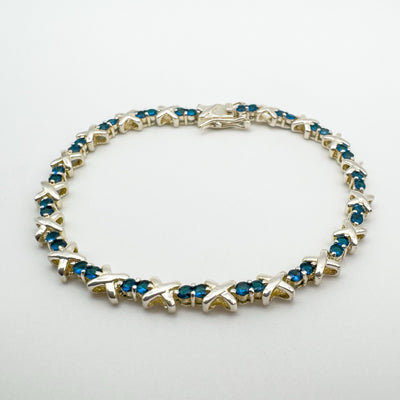 Side angle of sterling silver tennis bracelet with prong set blue CZs