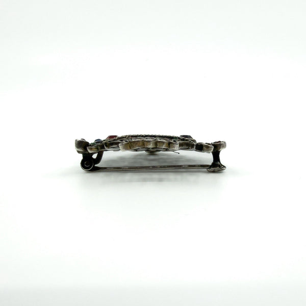 Side profile of giardinetti brooch showing closed pin and hook fitting and overall thickness.
