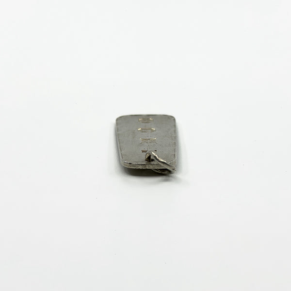 Side view of vintage sterling silver ingot pendant showing slim rectangular shape and jump ring.
