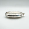 Side angle of engraved vintage silver locket showing floral etching and chunky shape