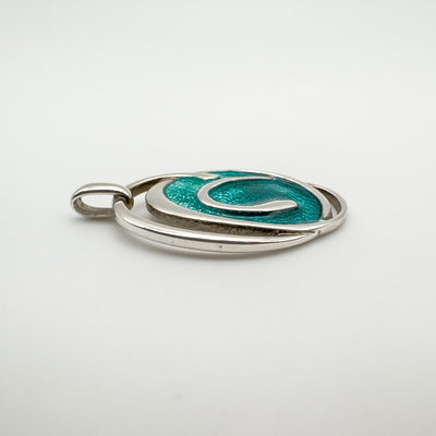 Side profile showing raised silver swirls on green enamel oval pendant