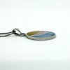 Side view of sterling silver oval inlay pendant showing thickness, bail and box chain connection.