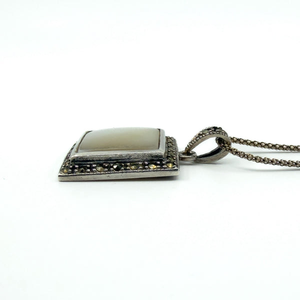 Side view of the sterling silver mother of pearl pendant, showing depth of the setting and marcasite edge.
