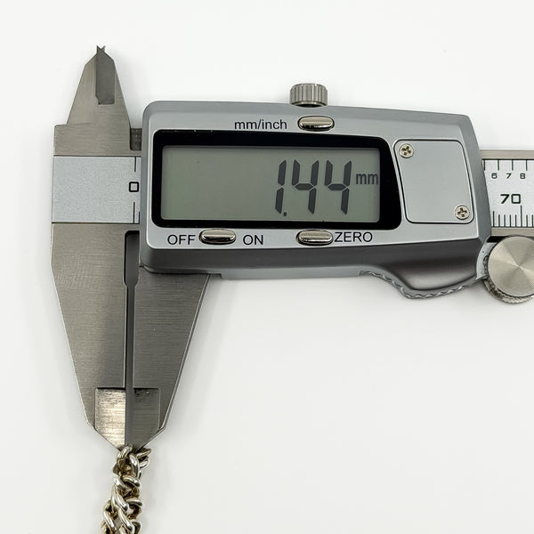 Digital caliper measuring the vintage sterling silver curb bracelet link depth at approximately 1.44mm.