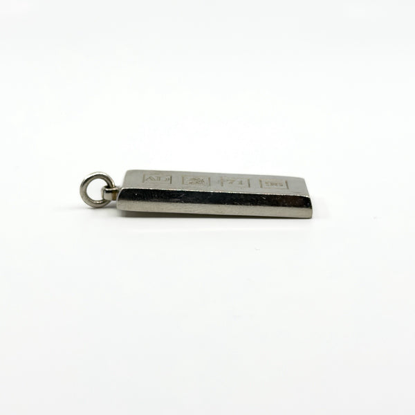 Angled side view of the silver ingot pendant showing the thick edge and hallmark panel.