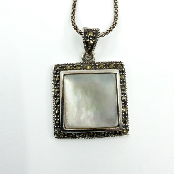 Sterling silver mother of pearl and marcasite square pendant close-up, showing bezel setting and stone border.